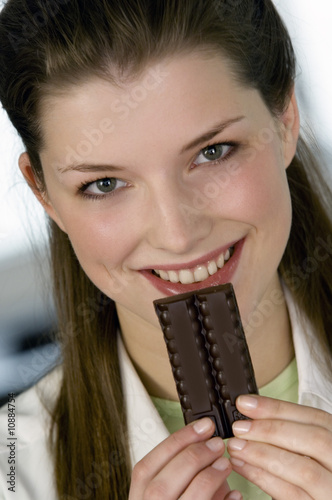 Foto: Portrait of a young smiling woman holding chocolate bar Portrait of a young smiling woman holding chocolate bar