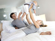 Parents and baby in bedroom, woman lifting her baby, indoors