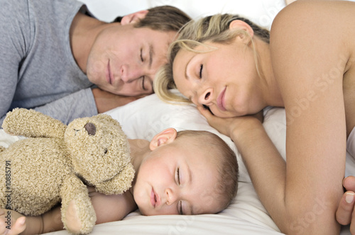 Photo: Father, mother and baby sleeping, indoors Father, mother and baby sleeping, indoors