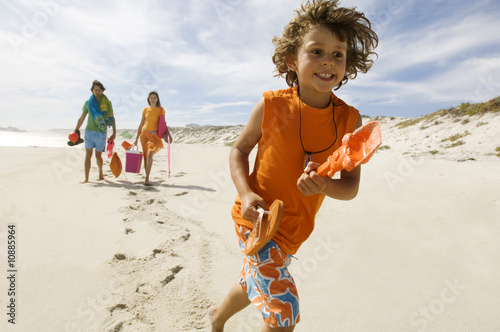 Photo: Parents and little boy walking on the beach, outdoors Parents and little boy walking on the beach, outdoors