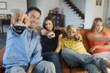 Parents and two teens holding eachothers a remote control, indoors