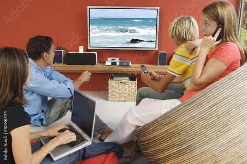 Photo: Parents and two teenagers watching television, indoors Parents and two teenagers watching television, indoors