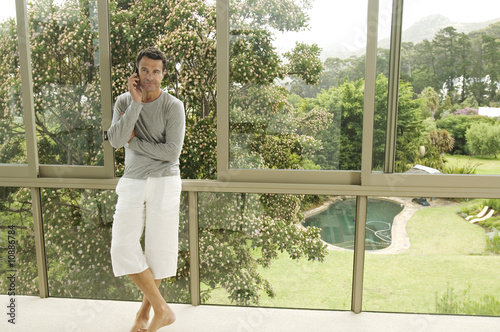 Photo: Man phoning, leaning against bay window Man phoning, leaning against bay window