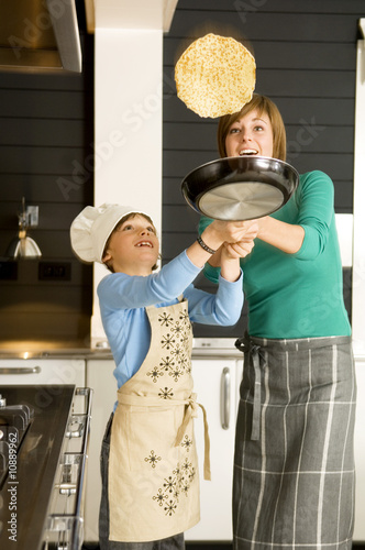 Photo: Young woman flipping a pancake with her son Young woman flipping a pancake with her son