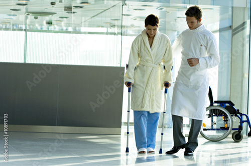 Photo: Male doctor assisting a female patient in walking on crutches Male doctor assisting a female patient in walking on crutches
