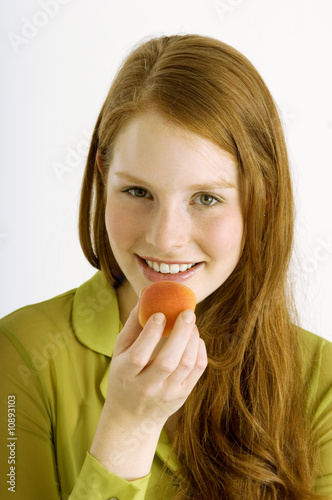 Photo: Portrait of a young woman eating an apricot and smiling Portrait of a young woman eating an apricot and smiling