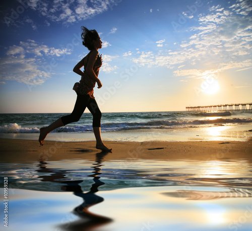 Photo: Woman running by the ocean at sunset Woman running by the ocean at sunset