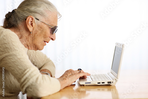 Elderly woman typing on laptop computer