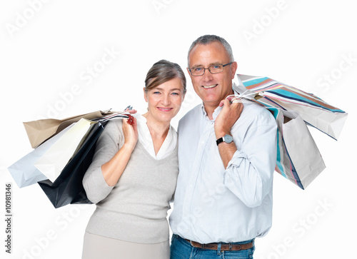 Happy older couple standing carrying bags