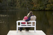 couple sitting on a bench at a lake in autum