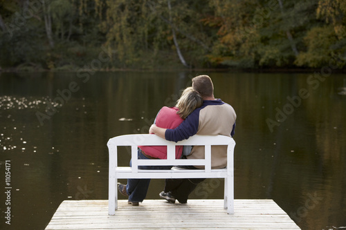 Photo: couple sitting on a bench at a lake in autum couple sitting on a bench at a lake in autum