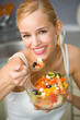 Portrait of young happy woman eating salad at kitchen Portrait of young happy woman eating salad at kitchen
