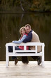 couple sitting on a bench at a lake in autumn