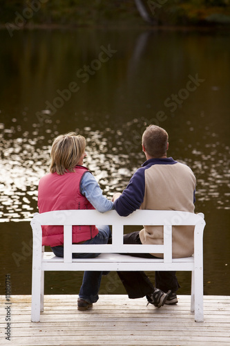 Photo: couple sitting on a bench at a lake in autumn couple sitting on a bench at a lake in autumn