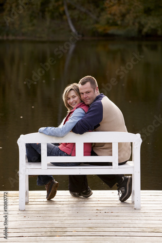 Photo: couple sitting on a bench at a lake in autumn couple sitting on a bench at a lake in autumn