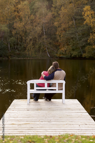 Photo: couple sitting on a bench at a lake in autumn couple sitting on a bench at a lake in autumn