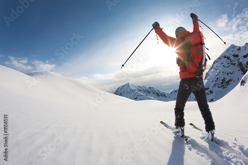 Photo: Skier reaches his arms up over a snowy mountain landscape Skier reaches his arms up over a snowy mountain landscape