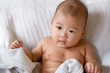 Baby sitting up in bed, looking away from camera