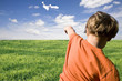 young boy flying a paper plane