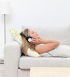 Closeup of a young woman lying on sofa and listening to music