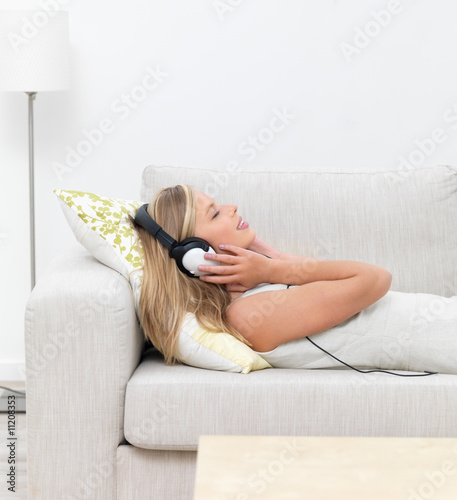 Foto: Closeup of a young woman lying on sofa and listening to music Closeup of a young woman lying on sofa and listening to music