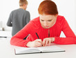 Young girl writing notes in the kitchen while man standing in th