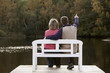 couple sitting on a bench at a lake in autumn