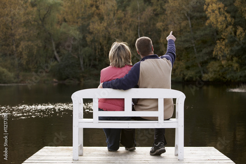 Photo: couple sitting on a bench at a lake in autumn couple sitting on a bench at a lake in autumn