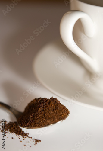 Photo: Spoon with coffee and white coffee cup Spoon with coffee and white coffee cup