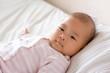 Baby lying in bed, smiling slightly