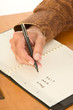 Hand of man writing in day planner about new life