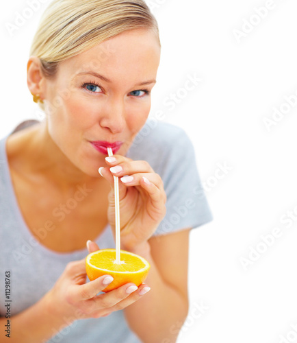 Young pretty girl sucking orange juice with a straw