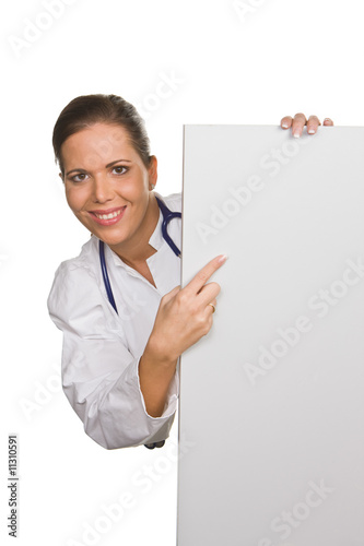 Foto: Young friendly doctor with an empty white poster Young friendly doctor with an empty white poster