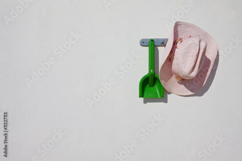 Foto: Cowboy hat and plastic shovel hanging on wall hook Cowboy hat and plastic shovel hanging on wall hook