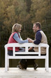 couple holding hands on a bench at a lake in autumn