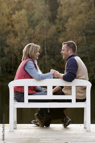 Photo: couple holding hands on a bench at a lake in autumn couple holding hands on a bench at a lake in autumn