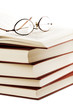 pile of books with glasses over it