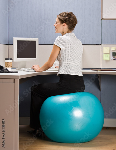 Photo: Businesswoman sitting on exercise ball at desk Businesswoman sitting on exercise ball at desk
