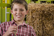 Portrait of boy standing by straw bale