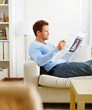 Man lying on couch reading newspaper