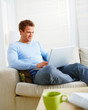 Young man working on laptop computer in living room