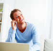 Joyful young man laughing and calling by phone