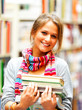 Foto: Pretty smiling lady holding books in library Pretty smiling lady holding books in library
