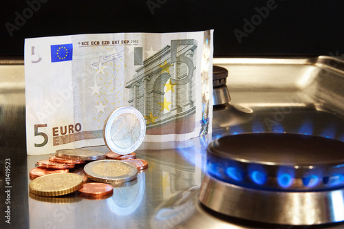 Geldschein und Münzen mit Gasflamme als Symbol für Energiekosten