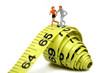 Miniature joggers run on a rolled up yellow measuring tape. Miniature joggers run on a rolled up yellow measuring tape.