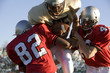 Defenders tackling running back carrying football