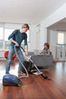 Man vacuum cleaning woman working
