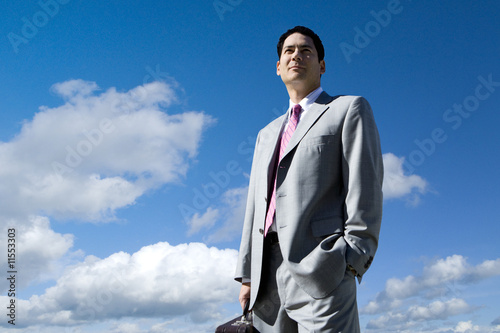 Photo: Businessman standing against blue sky Businessman standing against blue sky