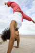 Young woman doing cartwheel on beach