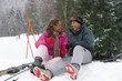 Mixed race couple sitting in snow on ski vacation